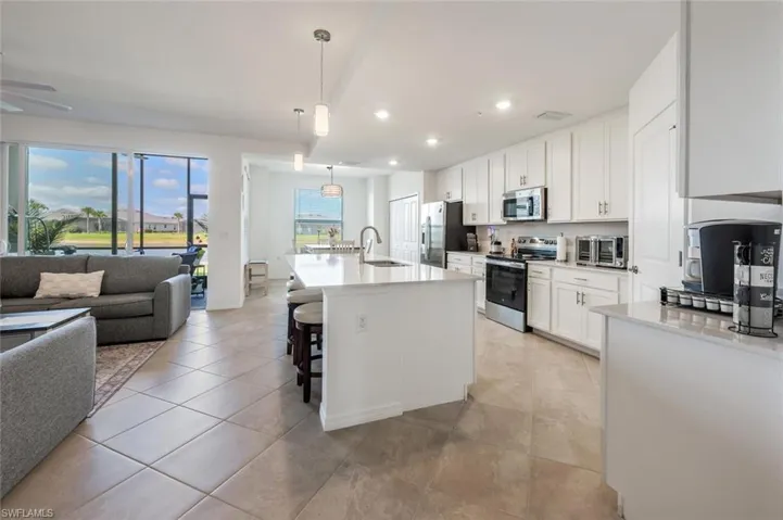 Kitchen featuring open floor plan, light countertops, stainless steel appliances, white cabinetry, and a sink