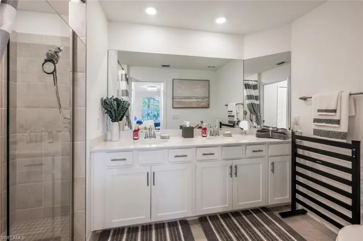 Full bath featuring vanity, recessed lighting, visible vents, and tiled shower