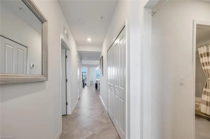 Hallway featuring light tile patterned flooring, visible vents, and baseboards