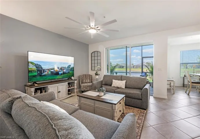 Living area with a wealth of natural light, baseboards, a ceiling fan, and light tile patterned floors