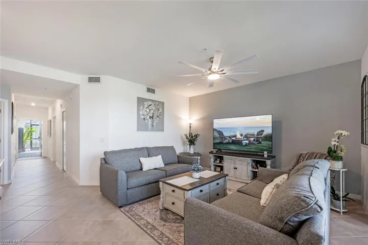 Living room featuring light tile patterned flooring, visible vents, baseboards, and a ceiling fan