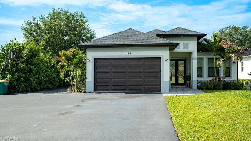 Contemporary stucco exterior featuring a two-car garage, paved driveway, and established landscaping