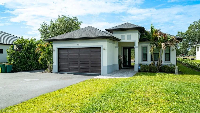 Modern exterior with a two-car garage, paved driveway, and established landscaping