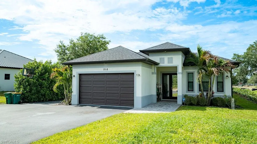 White stucco exterior with dark roofing and an attached two-car garage