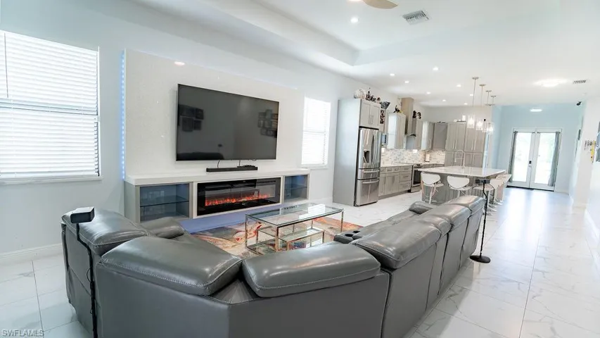 Open-concept living space with large format tile flooring and tray ceiling