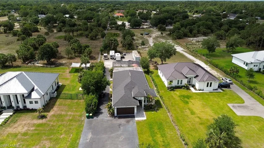Aerial perspective showcasing a property with a dark shingle roof and an attached garage