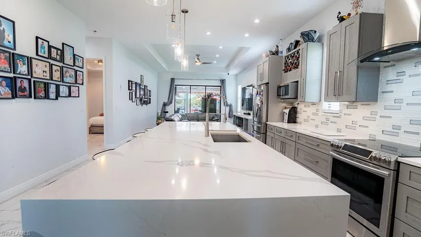 Kitchen featuring an expansive center island with an integrated sink and gooseneck faucet