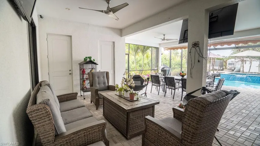 Expansive covered patio featuring a paver flooring, multiple ceiling fans, and integrated lighting