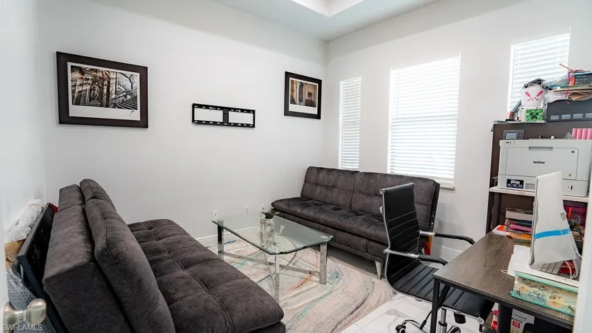 Room featuring multiple windows with blinds, white walls, and a tray ceiling