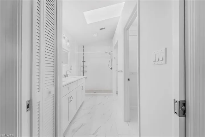 New Modern updated main bathroom with tiled floors, double sink high-top quartz vanity, newly tiled walk-in shower, vaulted ceiling with skylight.