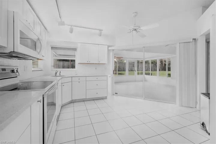 Kitchen with tiled backsplash, sliders out to enclosed lanai