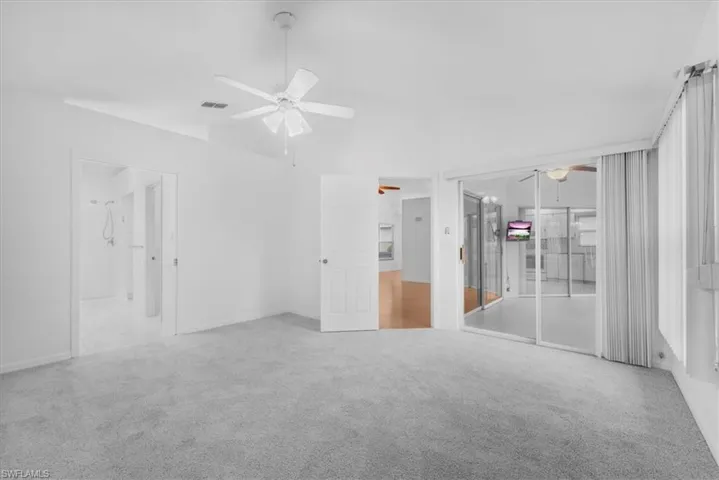 main bedroom with new carpet leading out to the enclosed lanai with new A/C