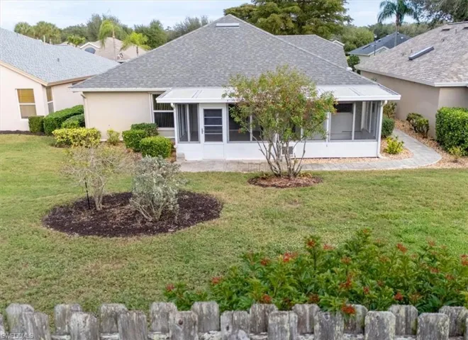 Rear view of house with roof with shingles, a lawn, and a sunroom