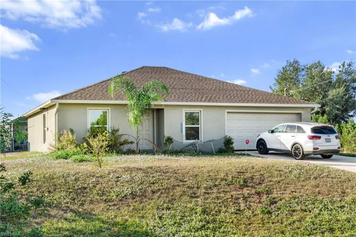 View of front of home featuring stucco siding, a garage, a shingled roof, concrete driveway, and a front lawn