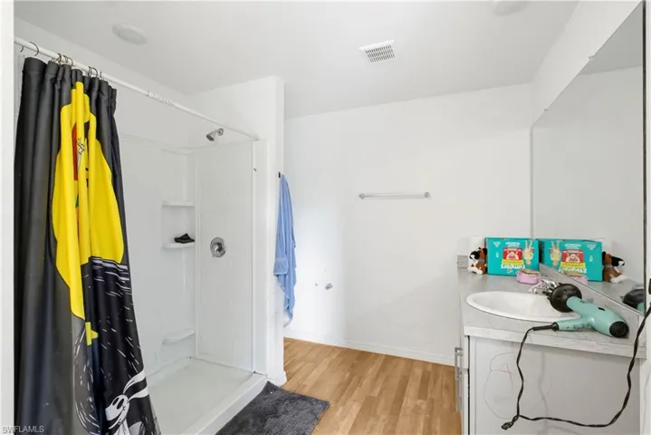 Full bathroom with vanity, a shower with shower curtain, and light wood-style floors