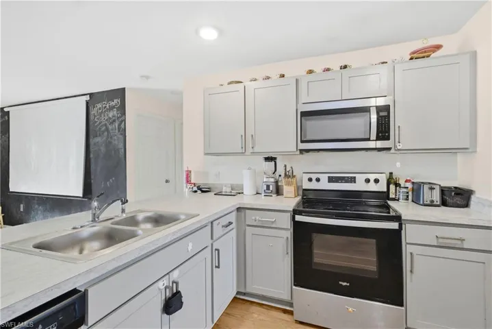 Kitchen featuring appliances with stainless steel finishes, gray cabinetry, light countertops, and light wood-type flooring