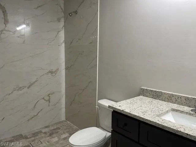 Bathroom with vanity, tiled shower, and toilet