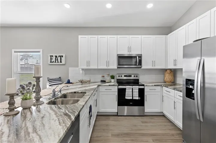 Kitchen with white cabinets, appliances with stainless steel finishes, sink, and light hardwood / wood-style floors