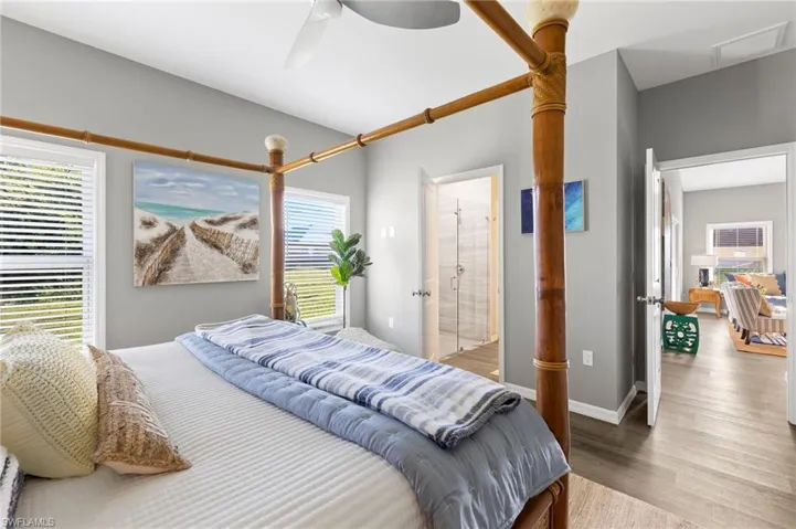 Bedroom with wood-type flooring, ensuite bath, ceiling fan, and multiple windows