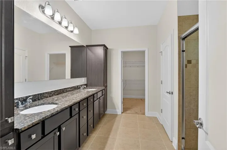 The primary bathroom with double sinks, storage and looking towards a large walk in closet