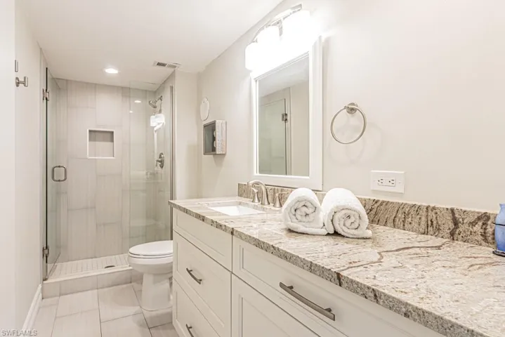 Full bath featuring a stall shower, vanity, toilet, recessed lighting, and marble finish floors
