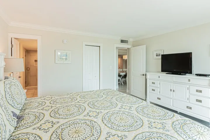 Tiled bedroom featuring crown molding and a closet