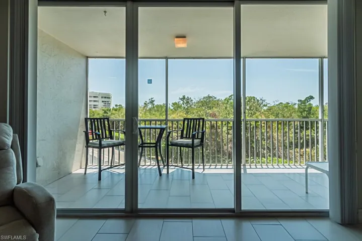 Doorway to outside with plenty of natural light, tile patterned floors, and a wall of windows