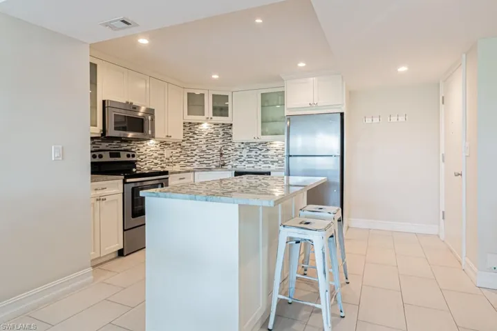 Kitchen featuring stainless steel appliances, decorative backsplash, baseboards, a kitchen island, and recessed lighting