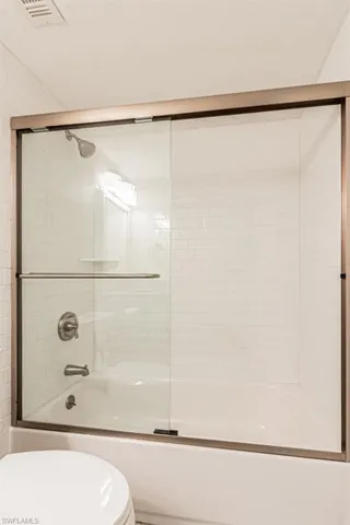 Full bath with toilet and shower / bath combination with glass door