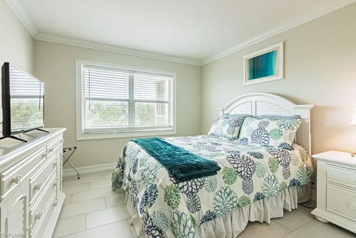 Bedroom featuring crown molding, baseboards, and light tile patterned floors
