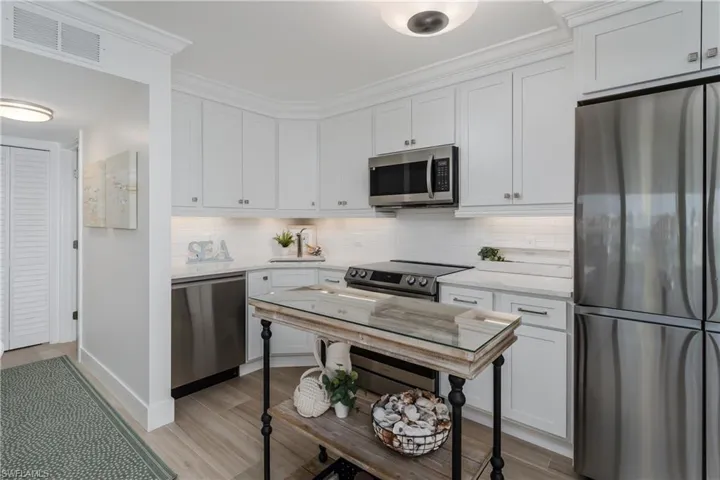 Kitchen with stainless steel appliances, tasteful backsplash, and white cabinets