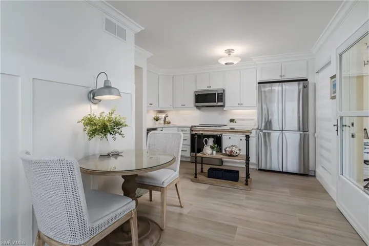 Kitchen featuring white cabinetry, tasteful backsplash, stainless steel appliances, and light hardwood / wood-style flooring