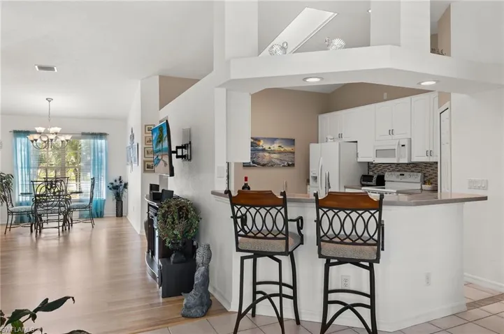 Kitchen with kitchen peninsula, white cabinets, a kitchen breakfast bar, light hardwood / wood-style flooring, and white appliances