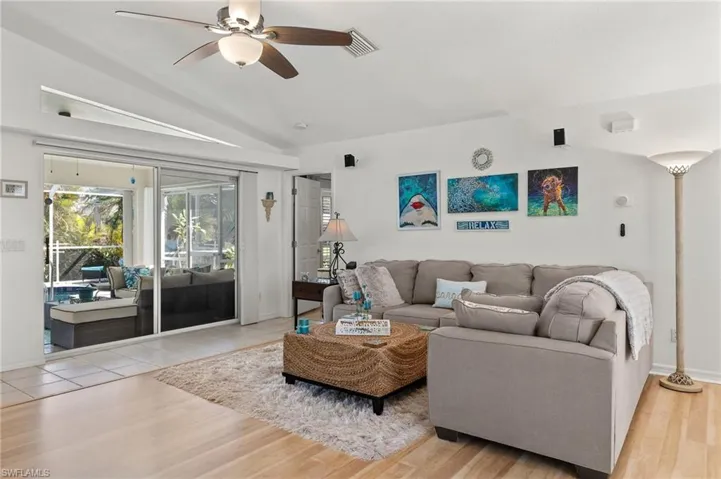 Living room with lofted ceiling, light wood-type flooring, and ceiling fan
