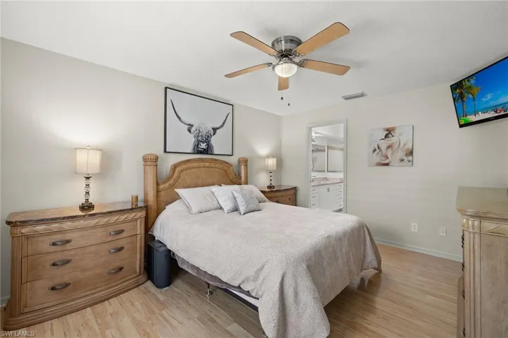 Bedroom with light hardwood / wood-style floors, ensuite bathroom, and ceiling fan