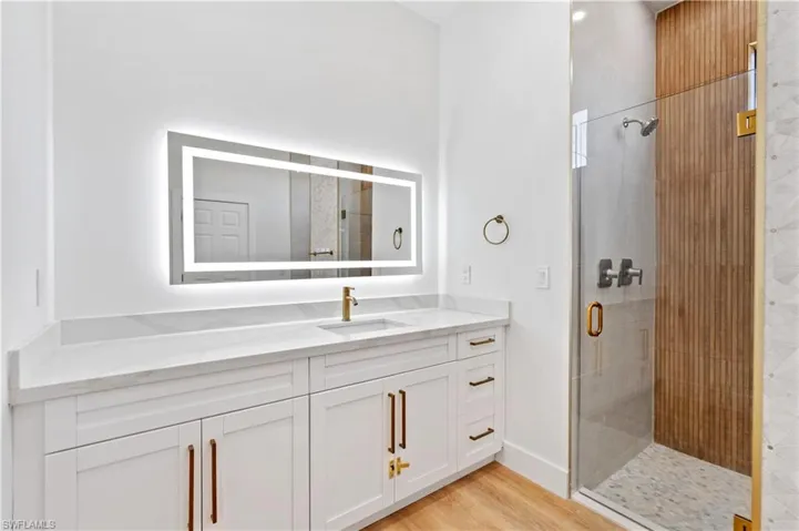 Bathroom featuring a shower stall, vanity, and light wood-style flooring