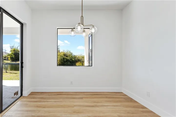 Unfurnished dining area with light wood finished floors, suspended lighting, plenty of natural light, and a water view