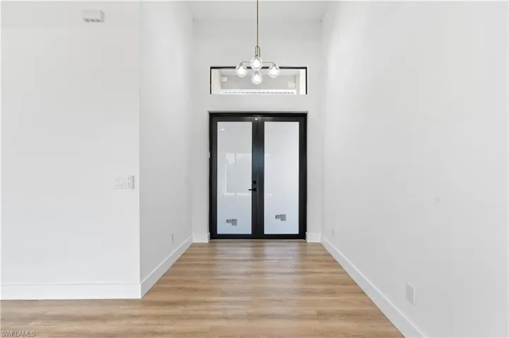 Entrance foyer featuring light wood-style flooring, a high ceiling, a chandelier, and french doors