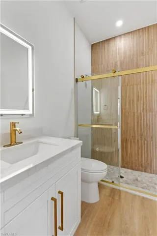 Full bath featuring a stall shower, vanity, and light wood-style flooring