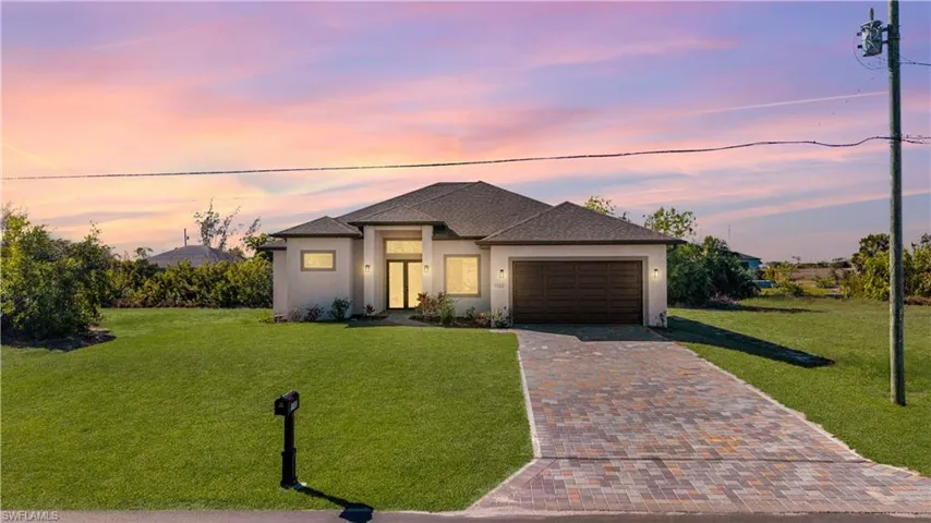 View of front of home with a front lawn, stucco siding, decorative driveway, roof with shingles, and a garage