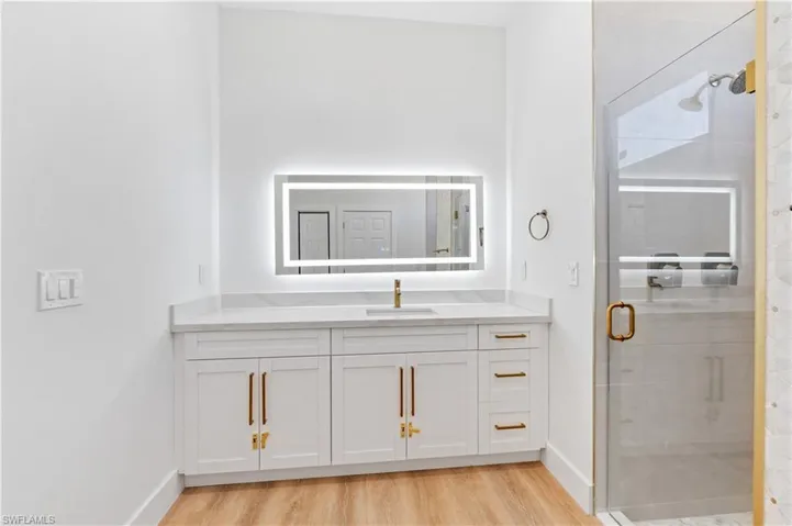 Full bath with a stall shower, vanity, and light wood finished floors