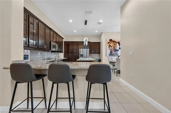 Kitchen featuring granite countertops, dark wood cabinetry, stainless steel appliances, and tile flooring