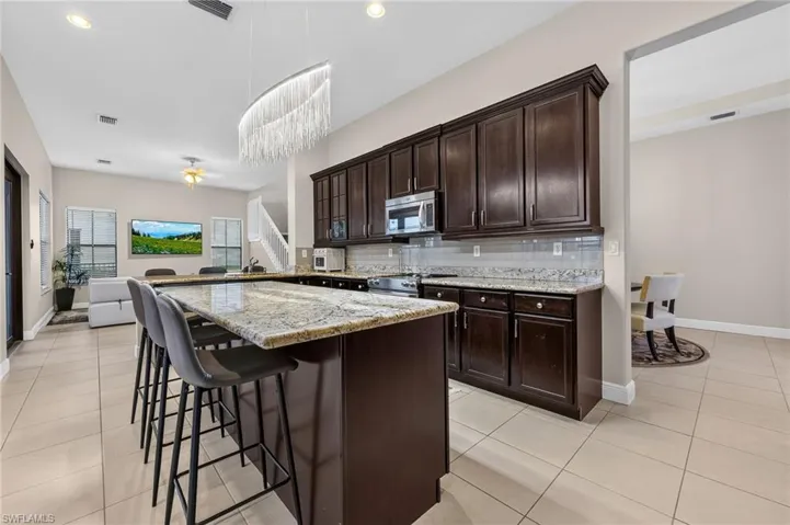 Kitchen featuring granite countertops, dark wood cabinetry, stainless steel appliances, and tile flooring