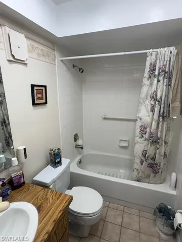 Full bathroom featuring shower / bath combination with curtain, light tile patterned floors, and vanity