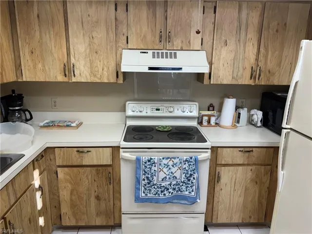 Kitchen featuring white appliances, extractor fan, and light countertops