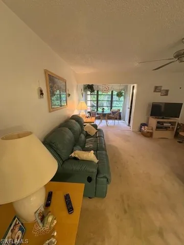 Living area with green leather sofa  and a ceiling fan.
