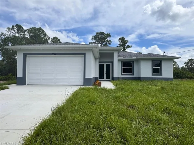 Ranch-style home with french doors, a garage, and a front lawn