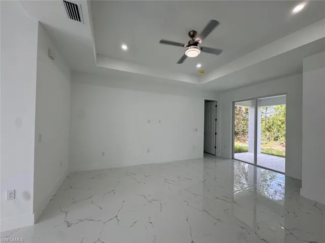 Unfurnished room featuring a raised ceiling and ceiling fan