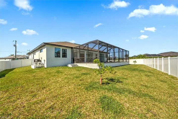 Back of house with a patio, glass enclosure, and a yard