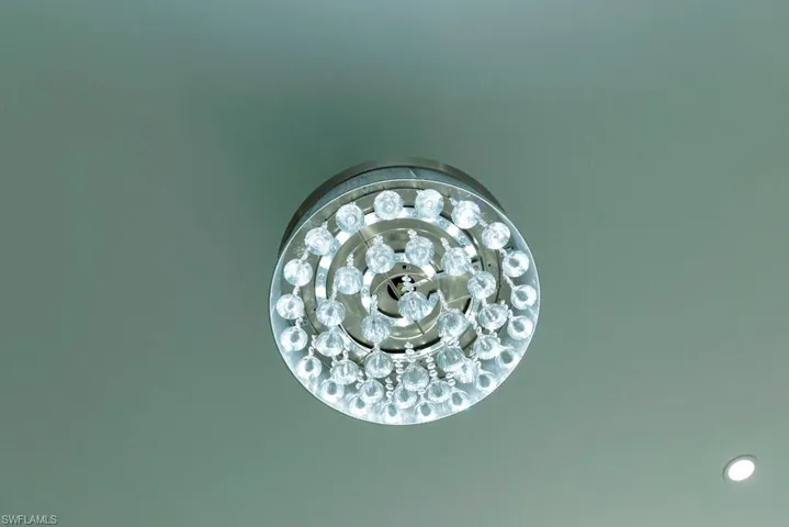Recessed crystal chandelier featuring multiple tiers of faceted glass elements and a chrome-finish base, complemented by a single recessed ceiling light fixture